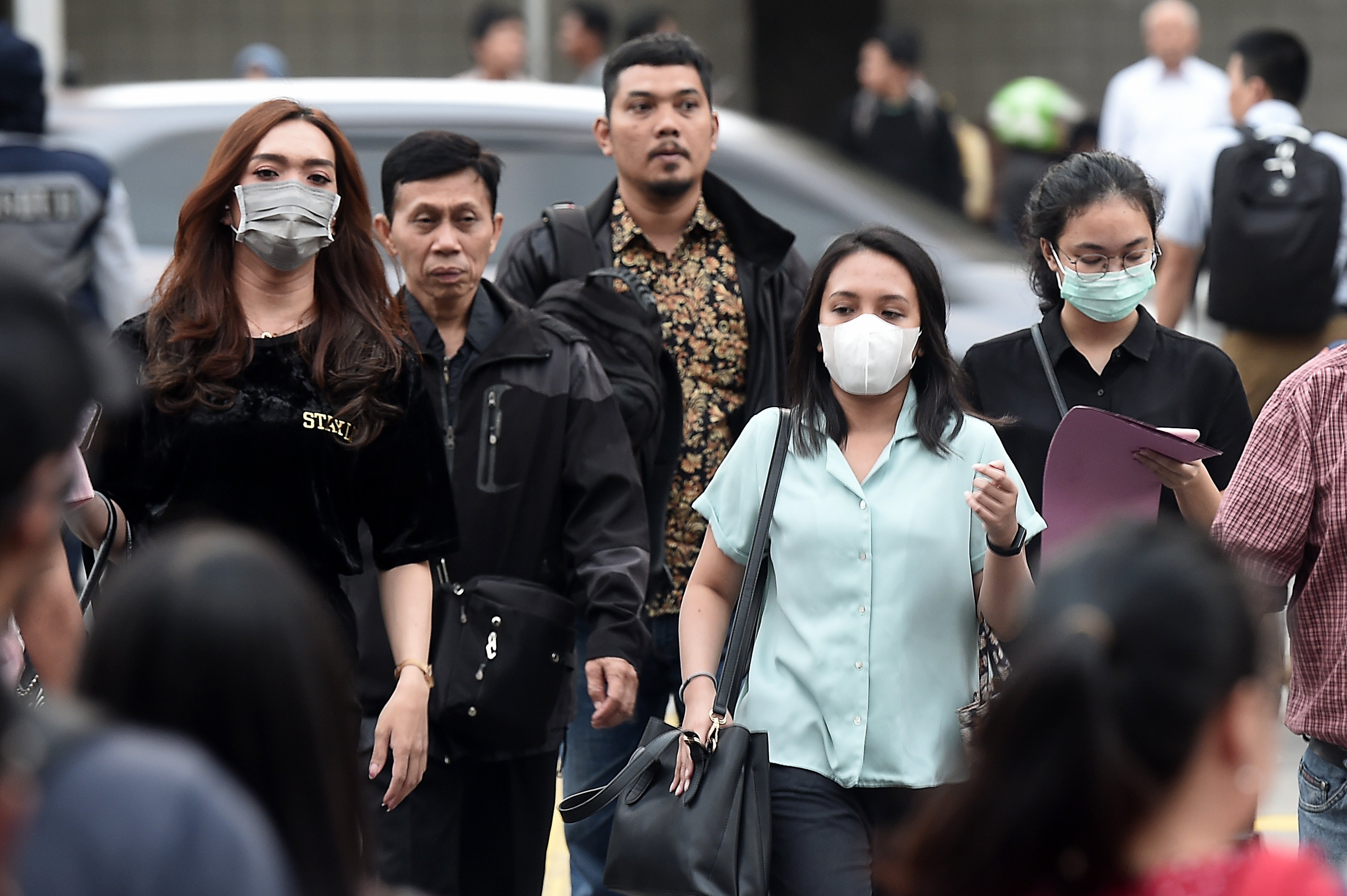 Sejumlah pejalan kaki memakai masker ketika melintas di kawasan Jalan Jenderal Sudirman, Jakarta.