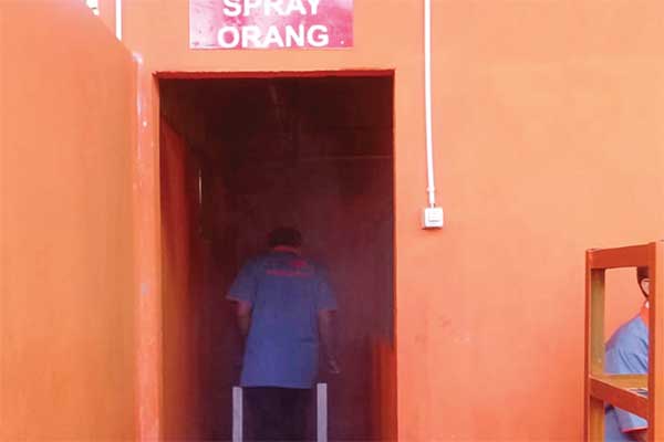 Pekerja melewati lorong yang berisi semprotan disinfektan di peternakan ayam Sekuntum di Desa Toto Projo, Kecamatan Probolinggo, Lampung Tim