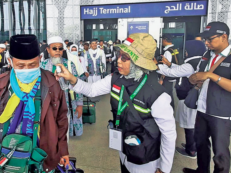 Petugas menyemprotkan air ke jemaah haji kloter pertama yang baru mendarat di Bandara Internasional Amir Muhammad bin Abdul Aziz, Madinah.