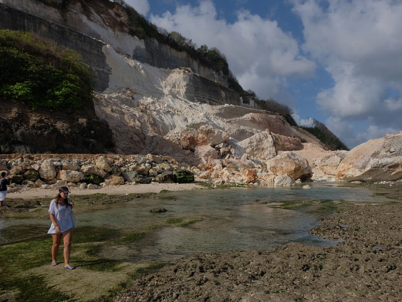Wisatawan melintas di dekat reruntuhan tebing akibat gempa bumi di kawasan obyek wisata Pantai Melasti, Badung, Bali.