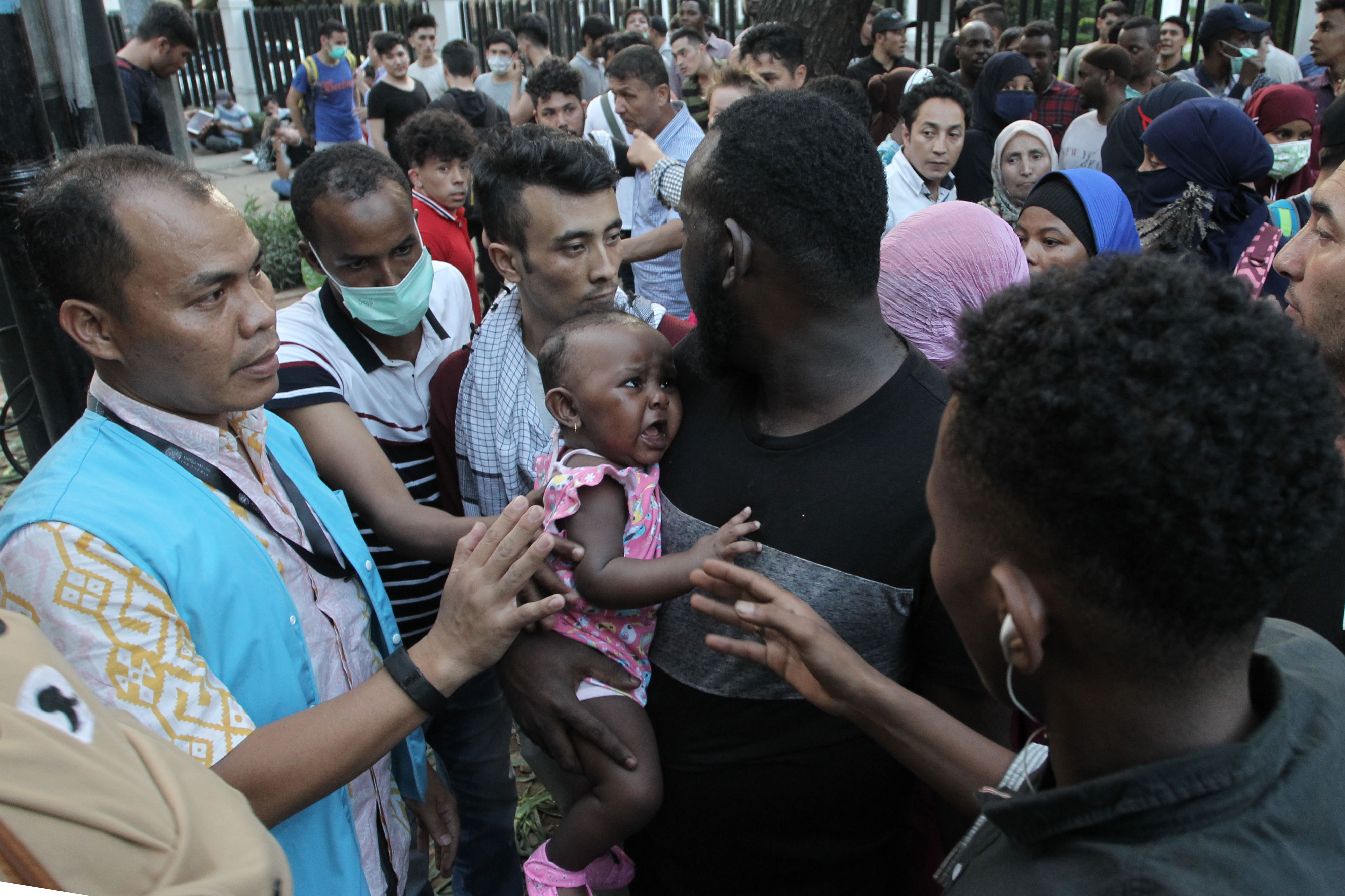 Para pencari suaka mengantre menuju bus untuk dipindahkan ke eks Gedung Kodim Kalideres, Jakarta.