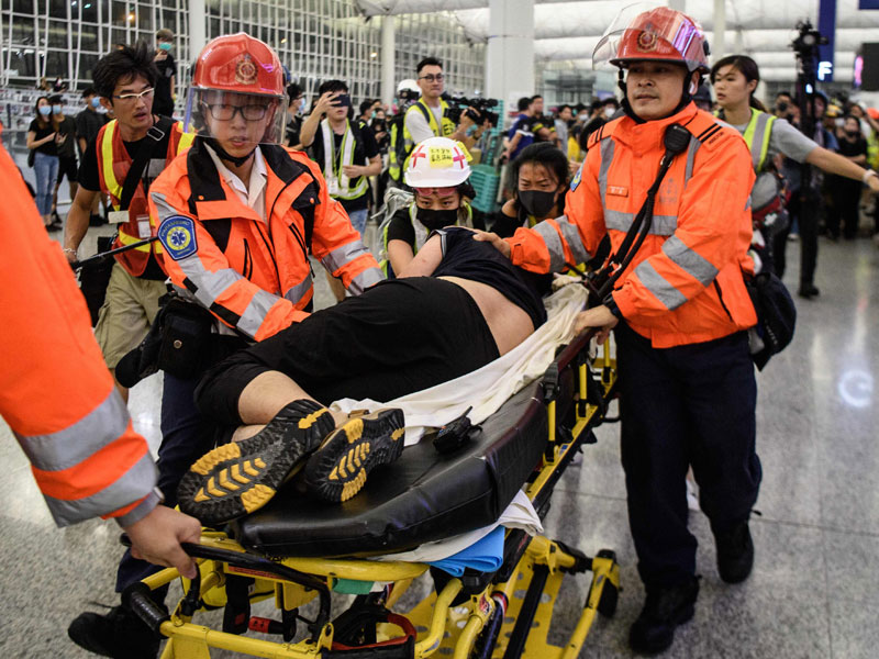 Seorang pria yang dicurigai oleh demonstran prodemokrasi sebagai mata-mata Tiongkok dievakuasi petugas kesehatan Bandara Hong Kong.
