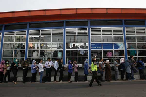 Calon penumpang bus TransJakarta antre hinga turun ke jalan di Halte Adam Malik, Petukangan, Jakarta Selatan, Rabu (3/10)
