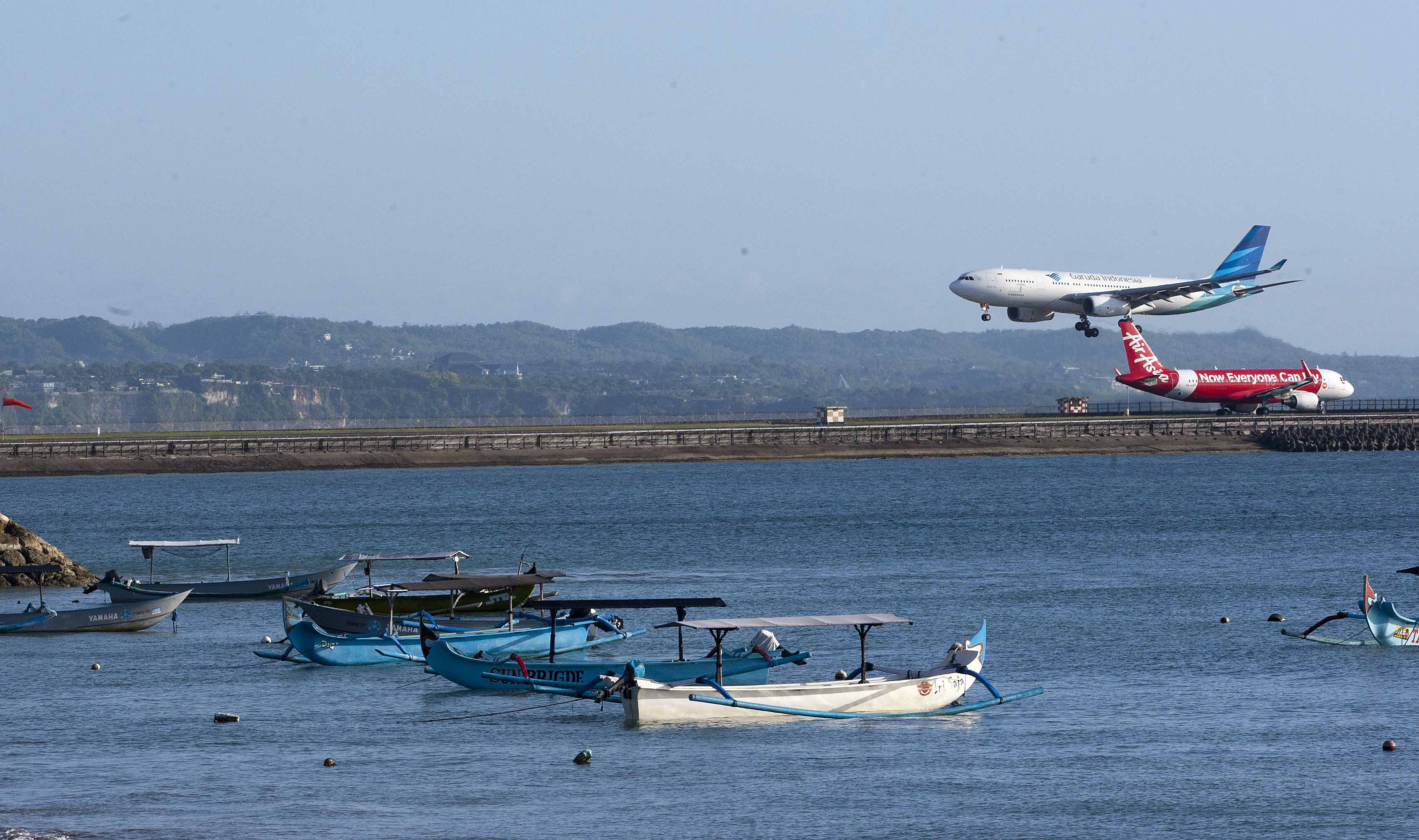 Pesawat Garuda saat akan mendarat, sementara pesawat AirAsia bersiap akan terbang di Bandara Ngurah Rai, Denpasar