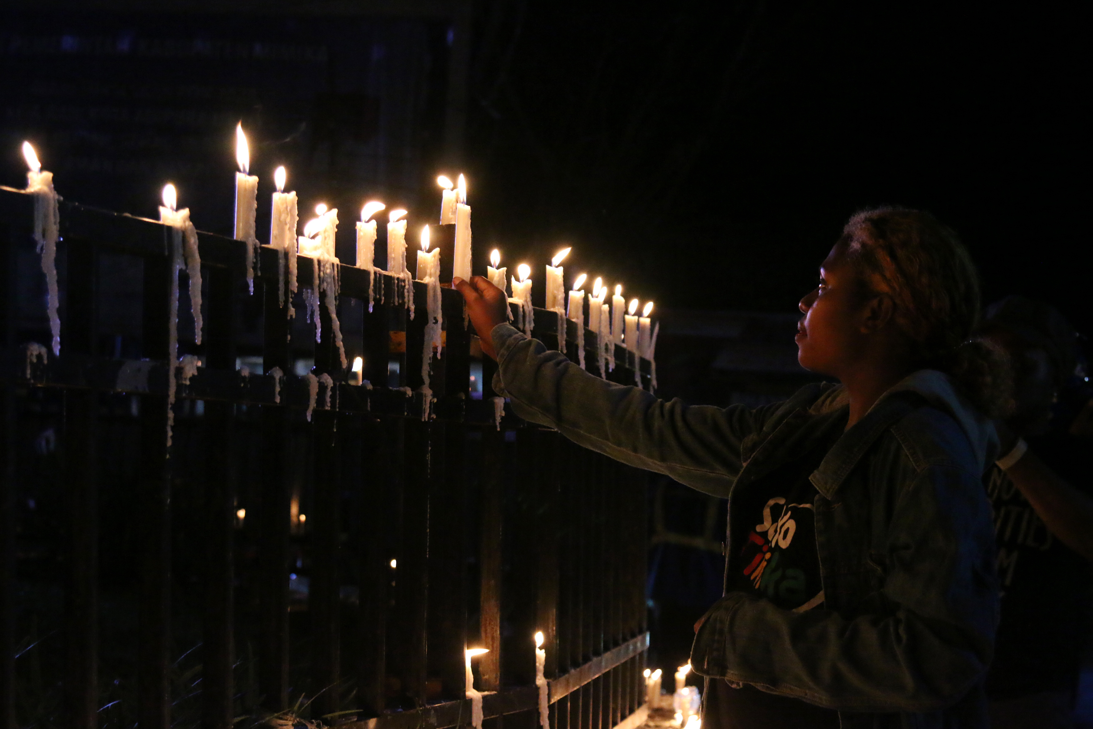 Warga Papua menyalakan lilin saat aksi damai di Bundaran Tugu Perdamaian Timika Indah, Mimika, Papua