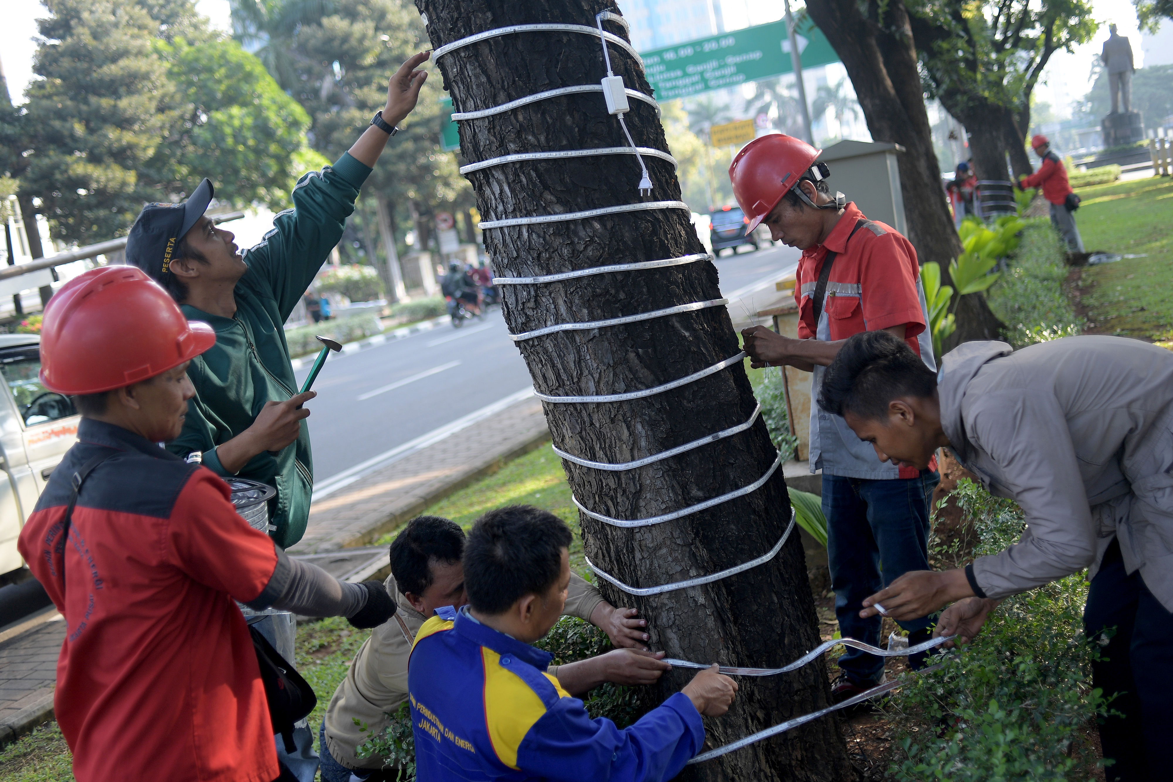 Petugas Suku Dinas Perindustrian dan Energi Jakarta Pusat memasang lampu hias di Jalan Medan Merdeka Selatan, Jakarta,