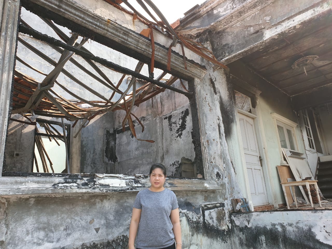 Eta Sihendra Djongroa di depan rumahnya yang hancur terbakar.