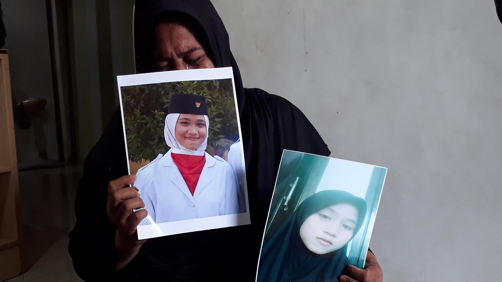 Kiftiah, 46, memegang foto-foto putrinya, Audry Viranti Islandi. Siswi kelas 2 SMK itu hilang sejak 14 hari lalu.