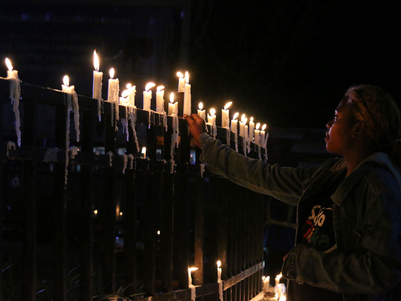 Warga Papua menyalakan lilin saat aksi damai di Bundaran Tugu Perdamaian Timika Indah, Mimika, Papua.