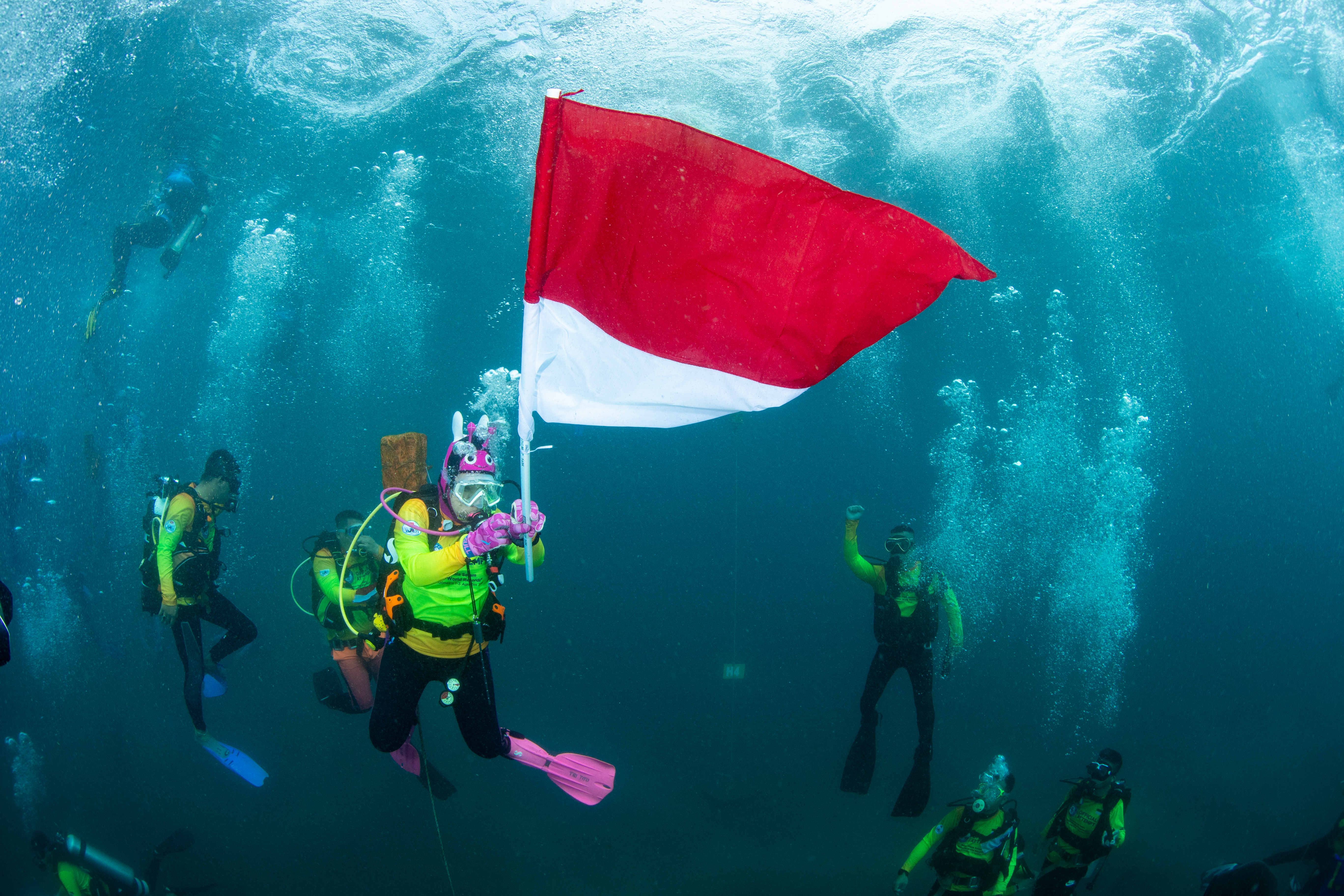Sejumlah penyelam Indonesia mengibarkan bendera Merah Putih di dasar laut.