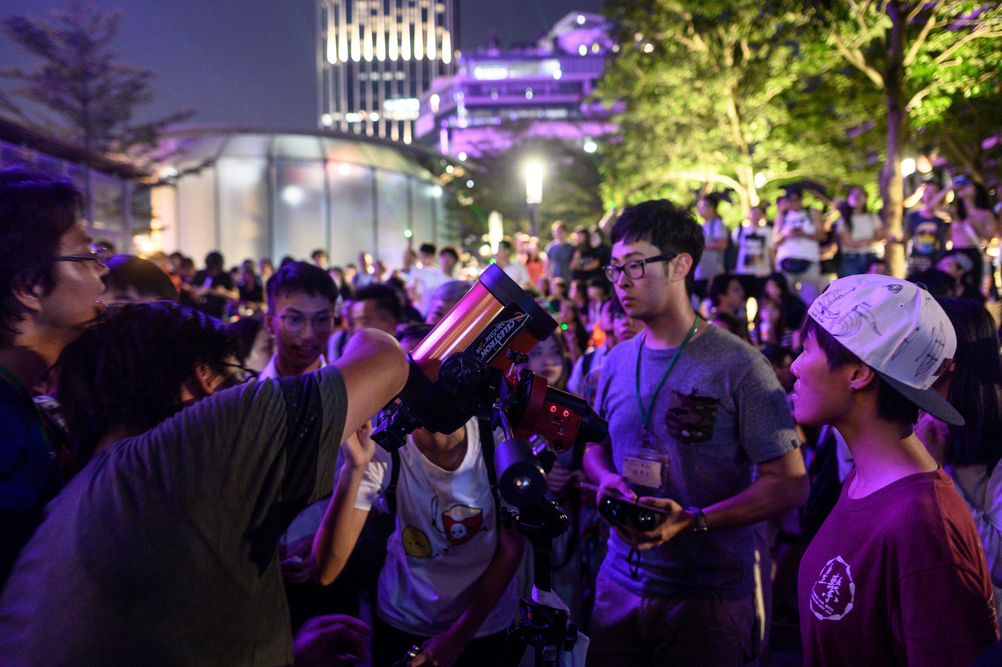 Orang-orang melihat melalui teleskop ketika pengunjuk rasa mengarahkan laser ke Space Museum saat demonstrasi di Hong Kong   7 Agustus 2019