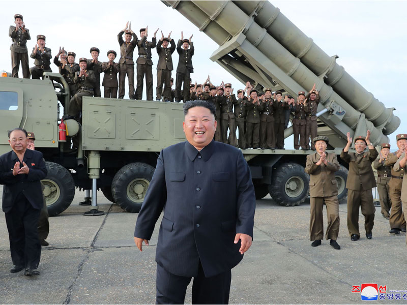 Pemimpin Korea Utara, Kim Jong-un (tengah), merayakan uji coba peluncuran rudal multipel superbesar di lokasi yang dirahasiakan di Korea Uta