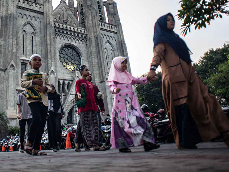 Warga berjalan menuju Masjid Istiqlal seusai memarkir sepeda motor di Gereja Katedral, Jakarta, kemarin. 