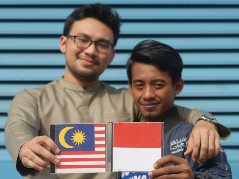 Seorang tenaga kerja Indonesia (kanan) bercengkerama dengan seorang tenaga kerja Malaysia.