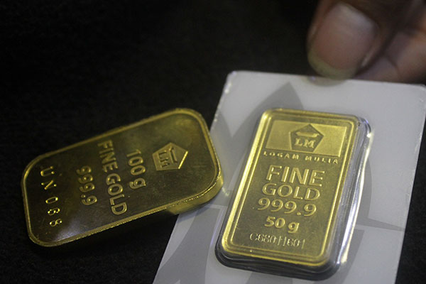 Pramuniaga menunjukkan emas batangan untuk investasi 