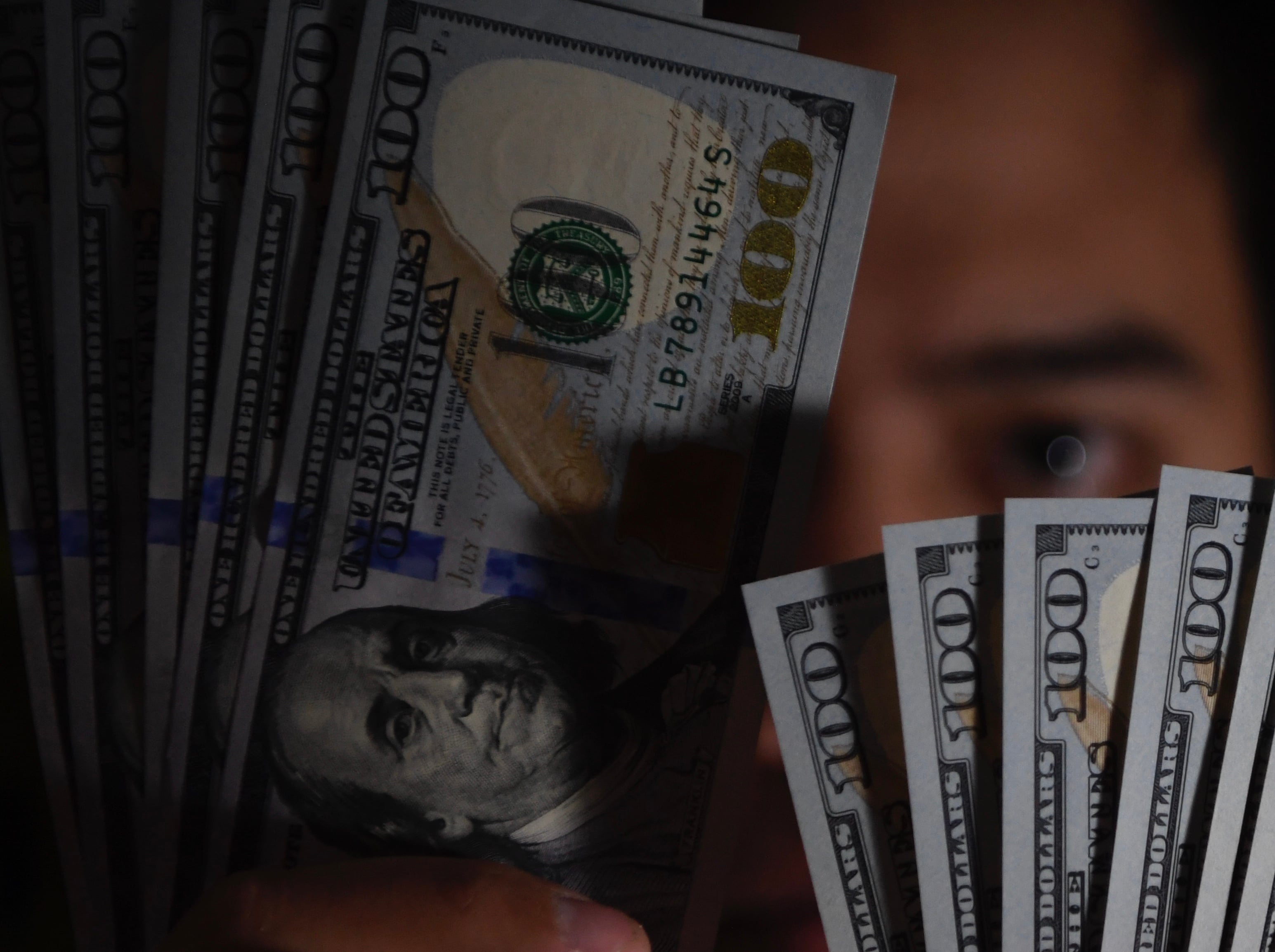 Seorang pembeli menunjukkan uang Dolar Amerika Serikat yang ditukarnya di gerai penukaran valuta asing, Jakarta