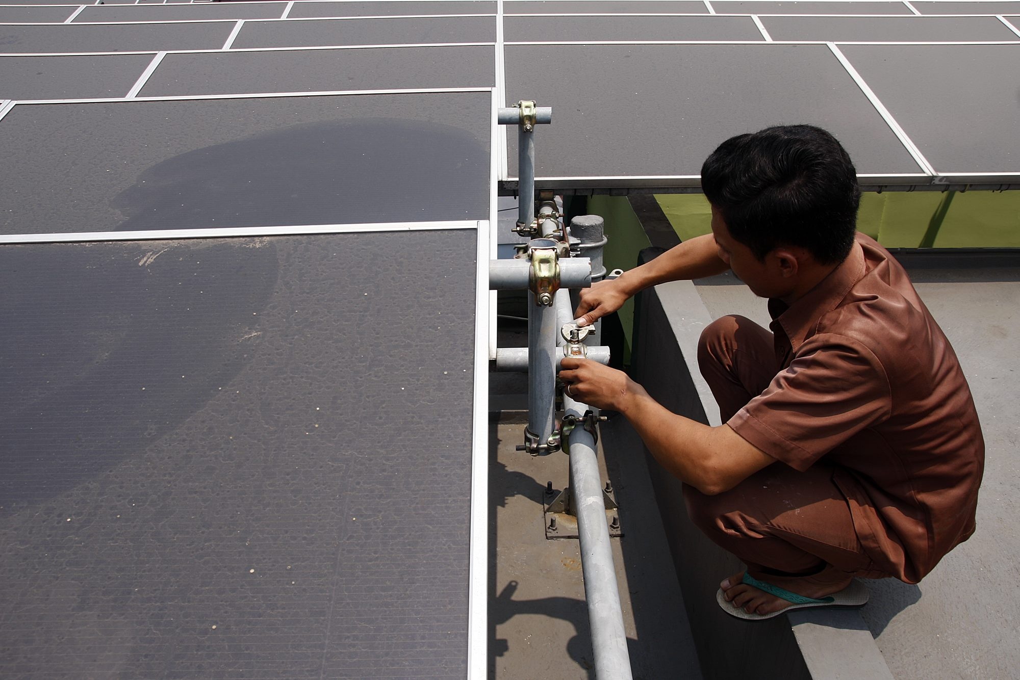 Petugas melakukan perawatan Pembangkit Listrik Tenaga Surya (PLTS) yang dipasang di sekolah menengah pertama (SMP) 19, Jakarta.