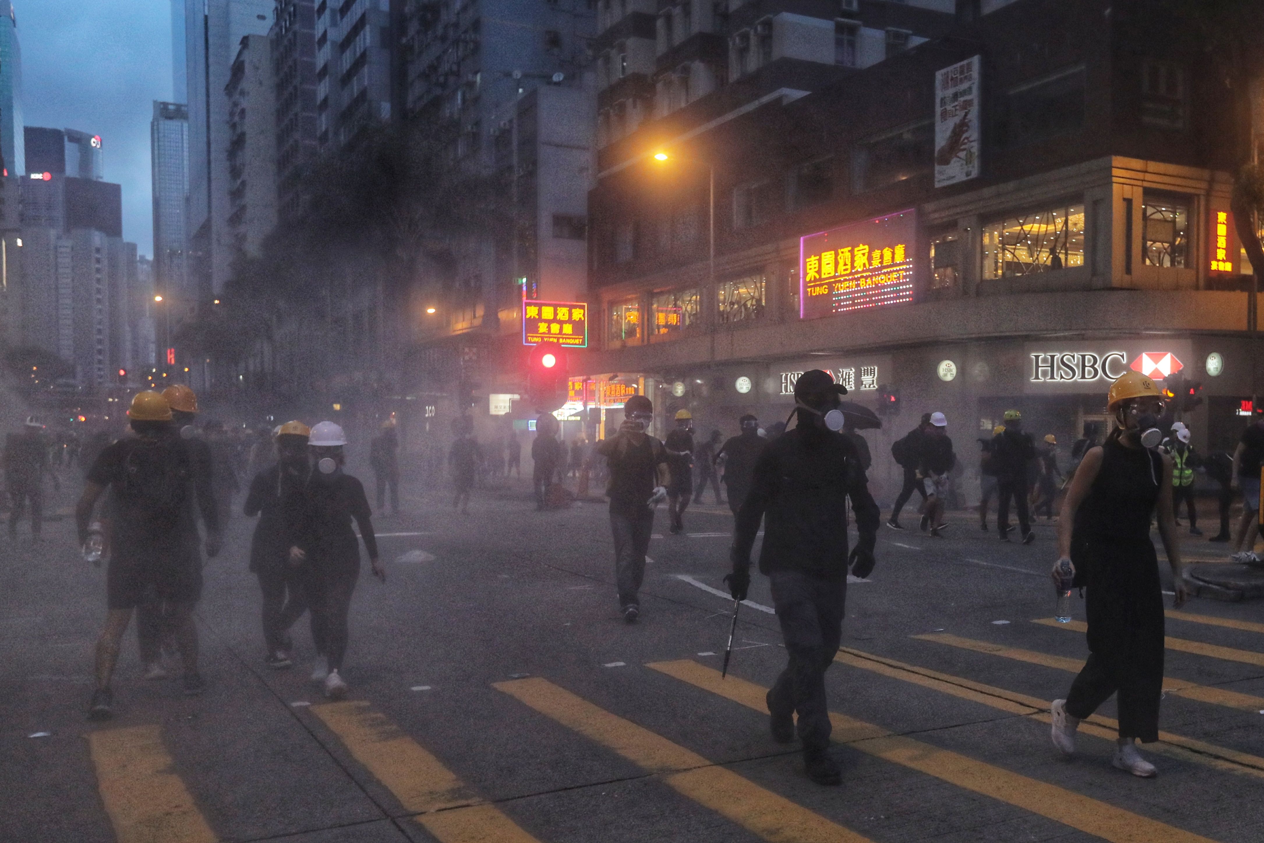 Demonstran berjalan melewat gas air mata yang ditembakkan polisi