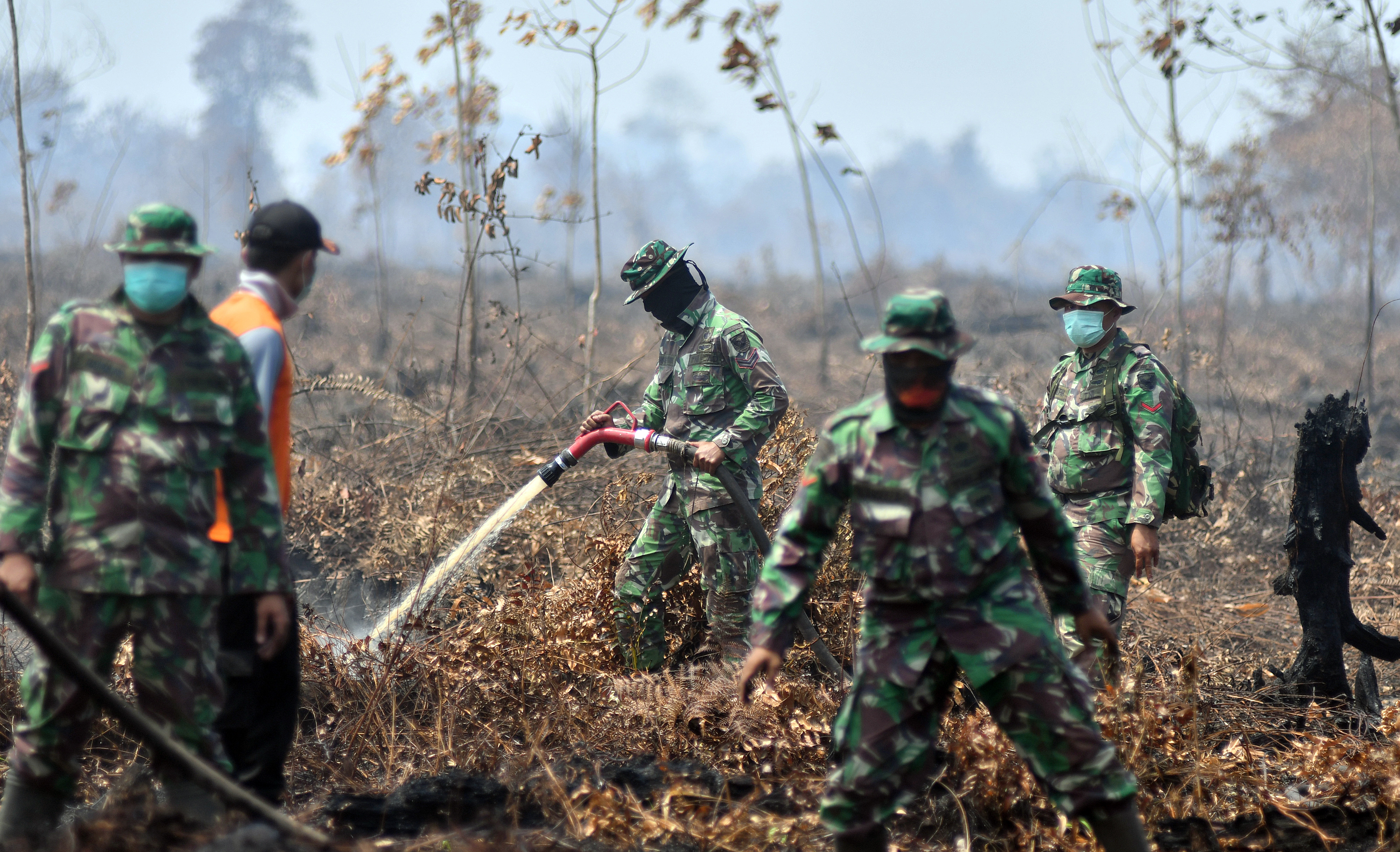 Prajurit TNI dan Petugas Badan Penanggulangan Bencana Daerah (BPBD) Muarojambi melakukan pendinginan di bekas lokasi lahan gambut