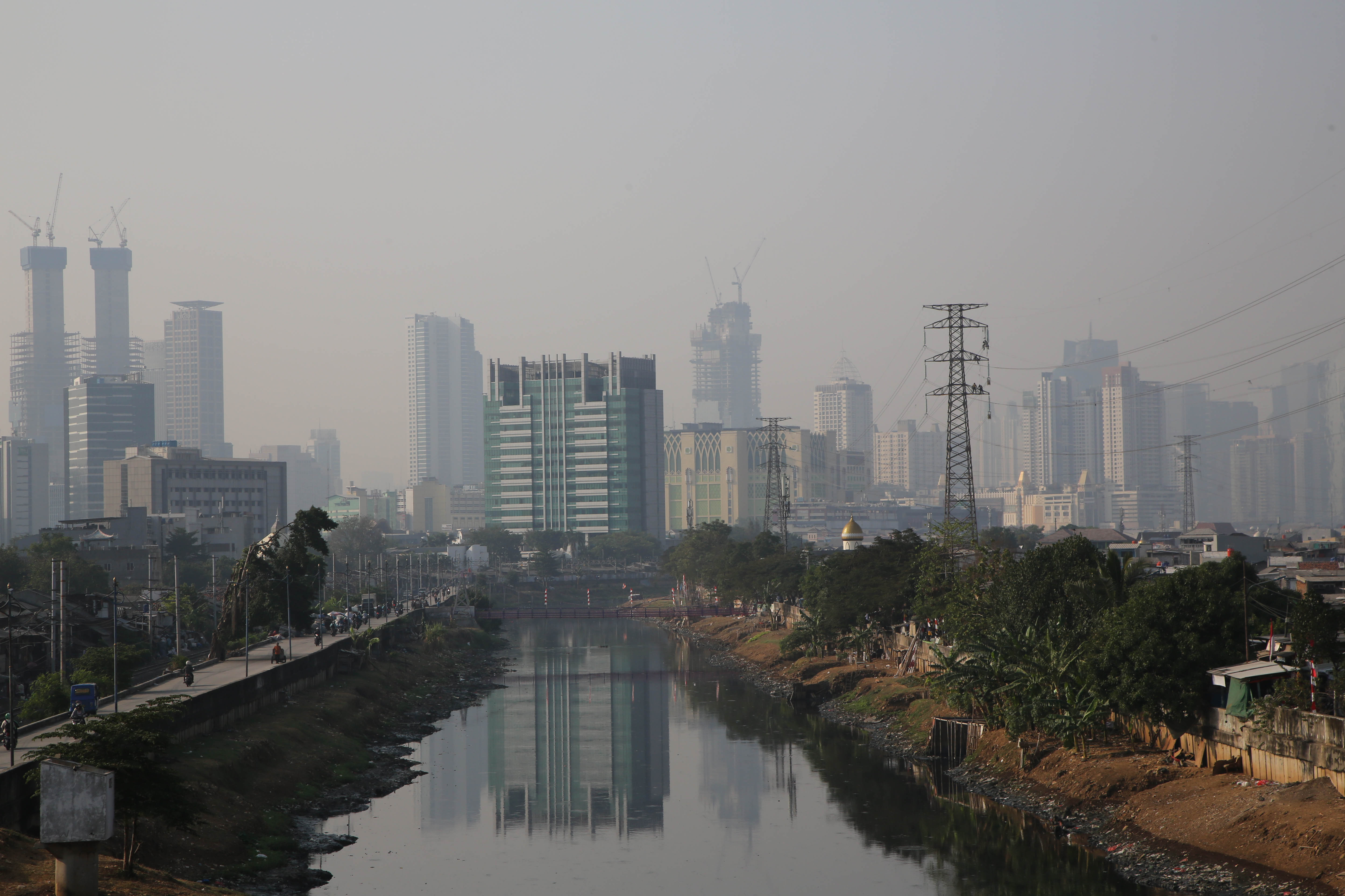Suasana kota Jakarta dengan latar belakang gedung bertingkat yang diselimuti asap polusi di kawasan Tomang, Jakarta.