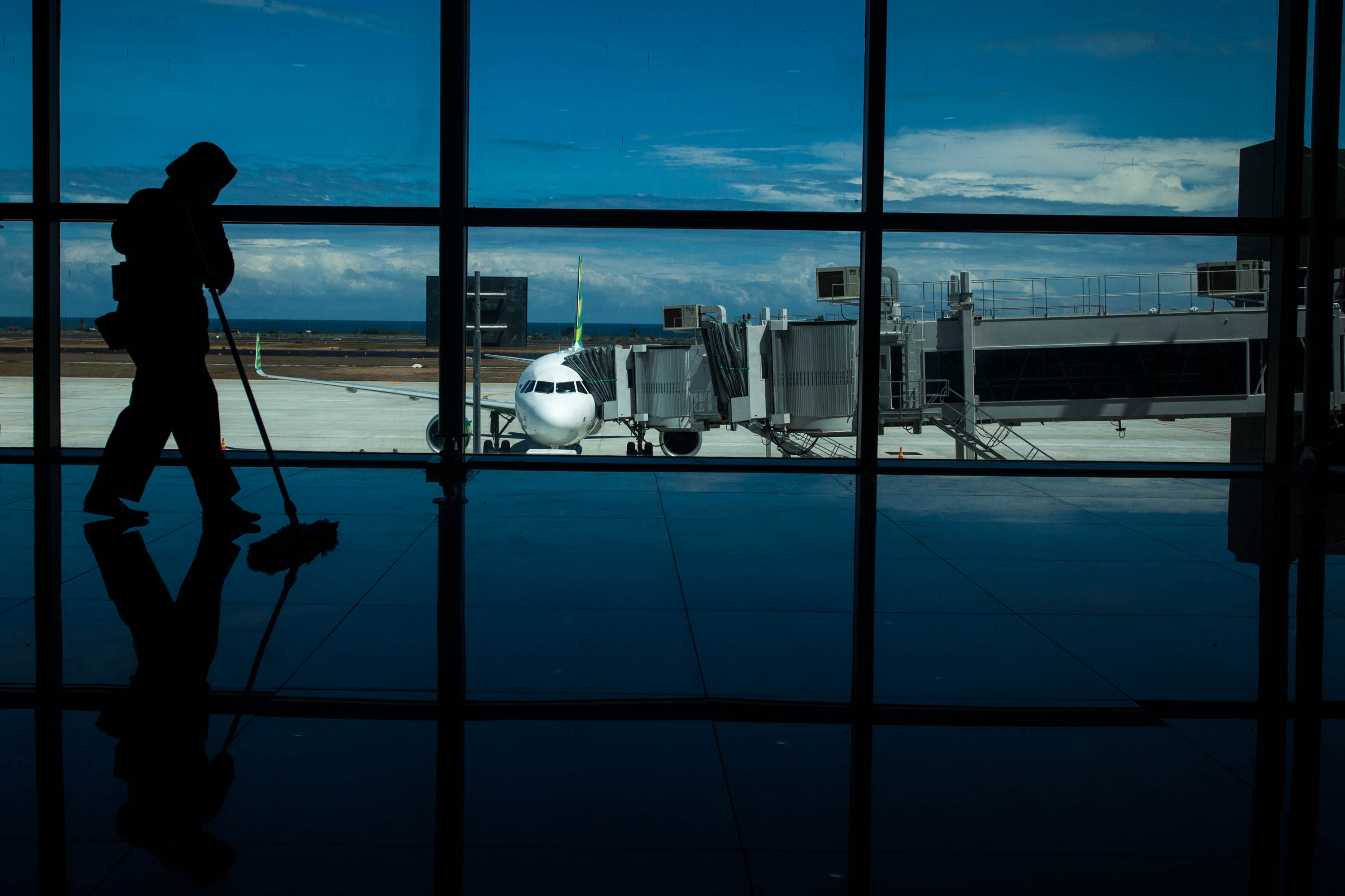 Petugas kebersihan bekerja dengan latar belakang pesawat komersial di Yogyakarta International Airport (YIA)  Kulon Progo, Mei lalu.