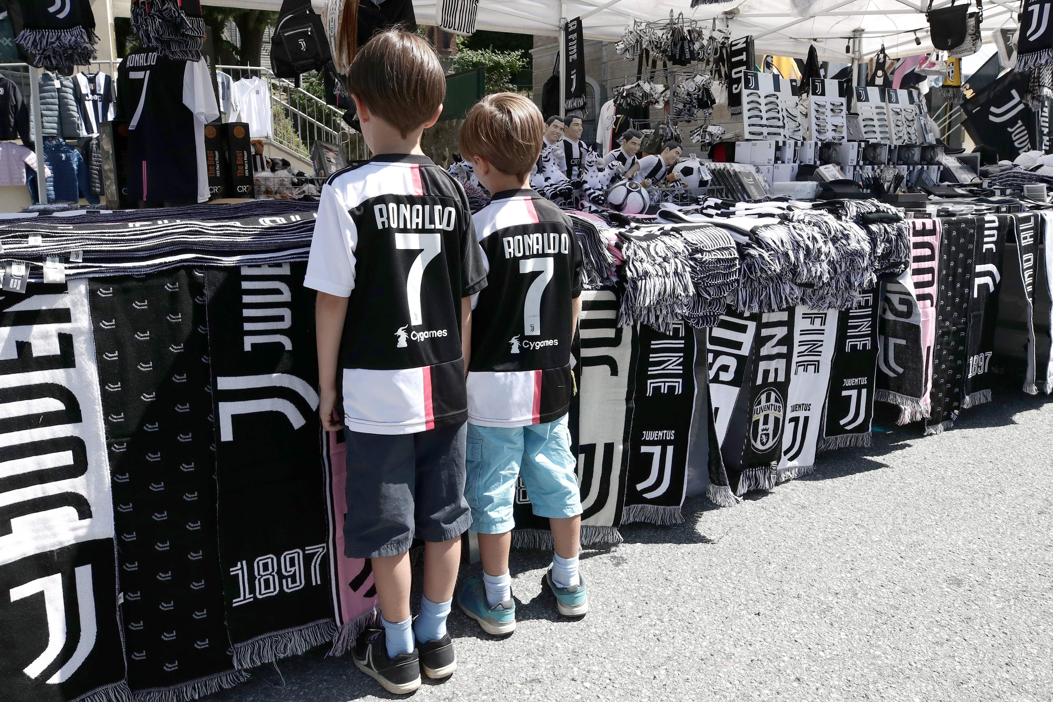 Dua anak mengenakan jersey Cristiano Ronaldo melihat pernak-pernik Juventus di Villar Perosa