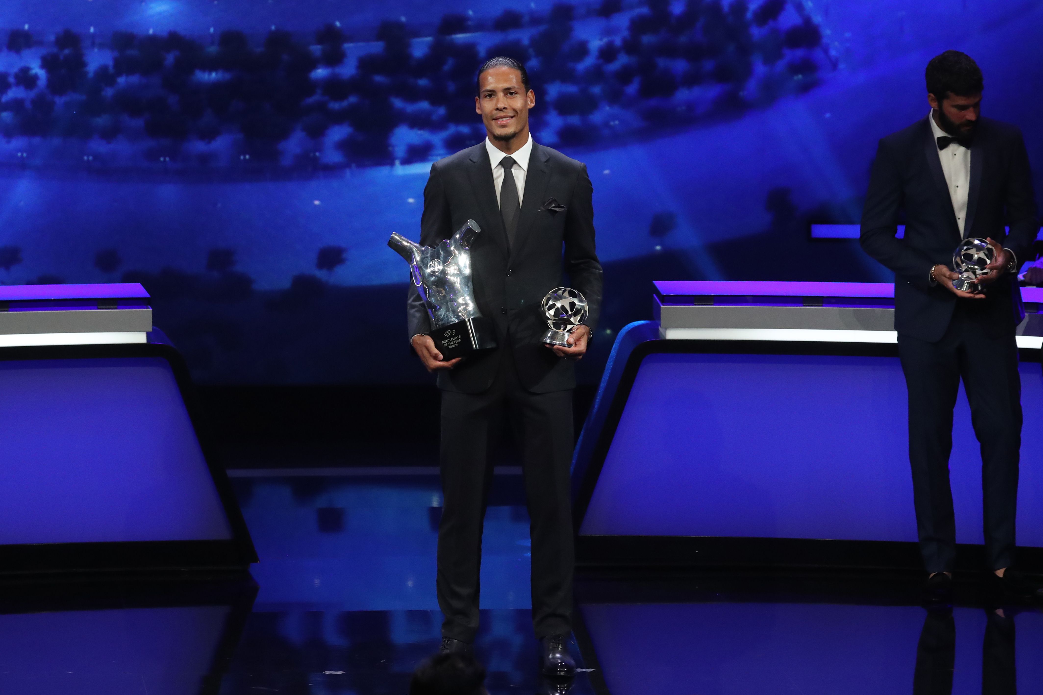 Virgil Van Dijk memegang trofi pemain terbaik UEFA dan bek terbaik Liga Champions.