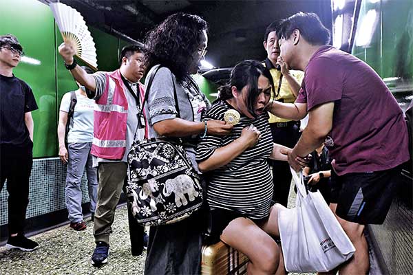 Seorang pria menenangkan istrinya yang tengah hamil di peron kereta bawah tanah mass transit railway (MTR) setelah pengunjuk rasa memblokir 
