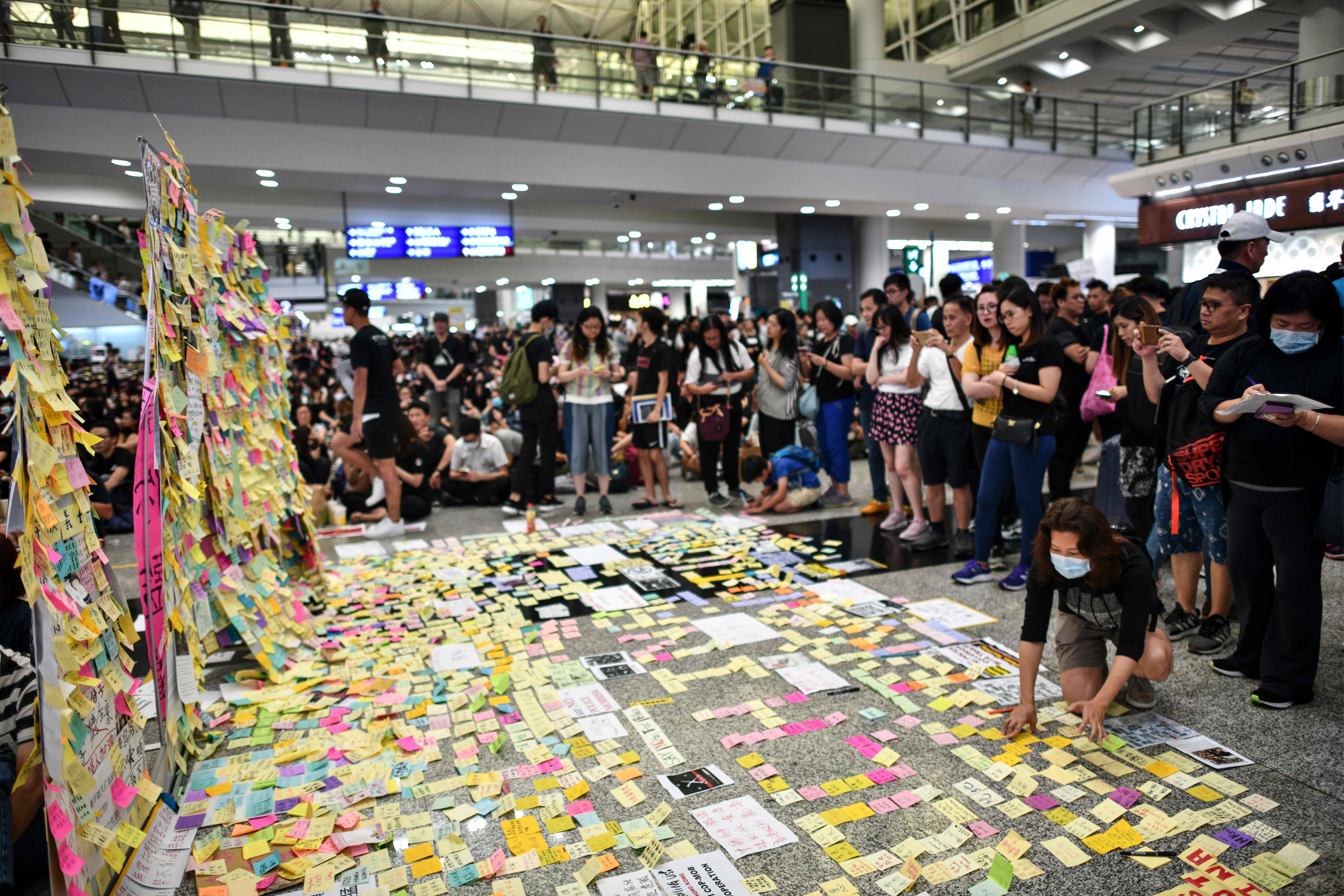 Para demonstran melakukan aksi di terminal kedatangan Bandara Hong Kong