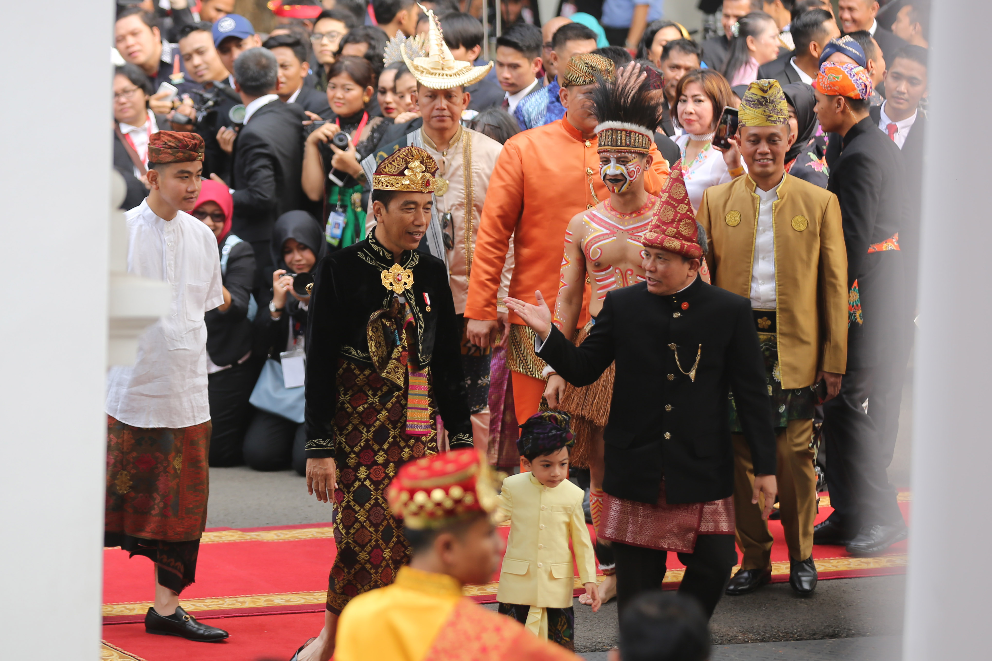Presiden Joko Widodo mengenakan pakaian adat Bali menggandeng cucunya, Jan Ethes di Istana Merdeka, Sabtu (17/8).