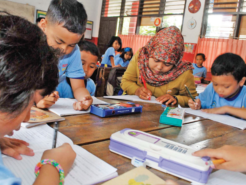 Guru (tengah) berinteraksi pada kegiatan belajar mengajar