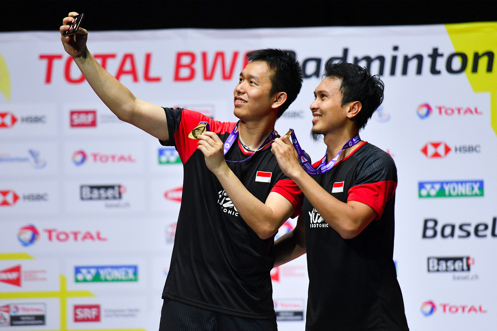 Juara dunia ganda putra Hendra Setiawan sedang memegang ponsel untuk berswafoto dengan rekannya Mohammad Ahsan. 