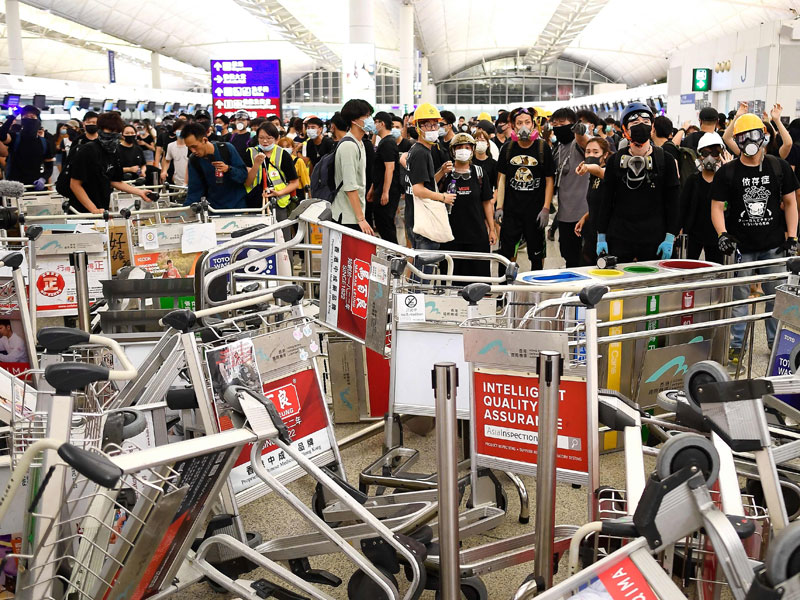 Para pengunjuk rasa menutup jalan masuk menuju terminal bandara setelah bentrok denagn polisi bandara Hong Kong.