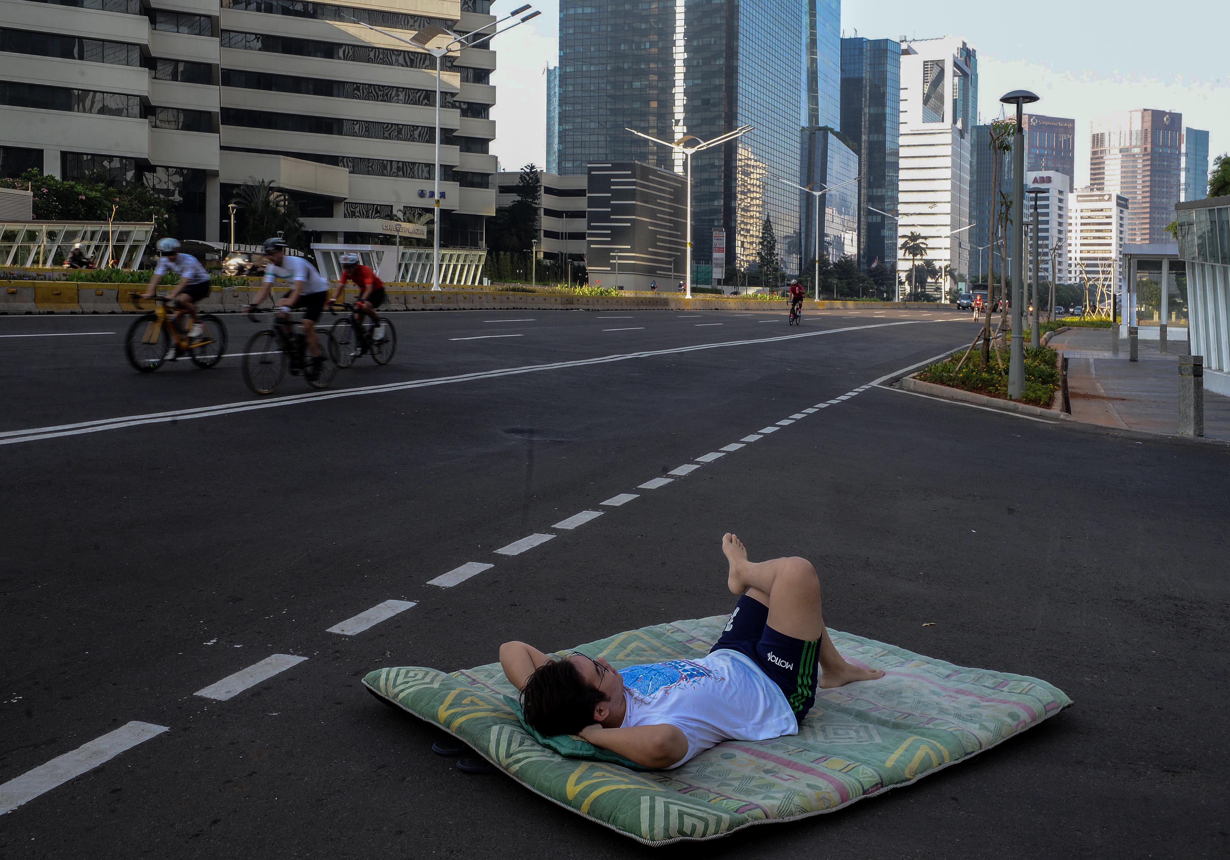 Warga berpose aktifitas keseharian dengan latar belakang suasana lengang Jakarta di kawasan Sudirman, Jakarta