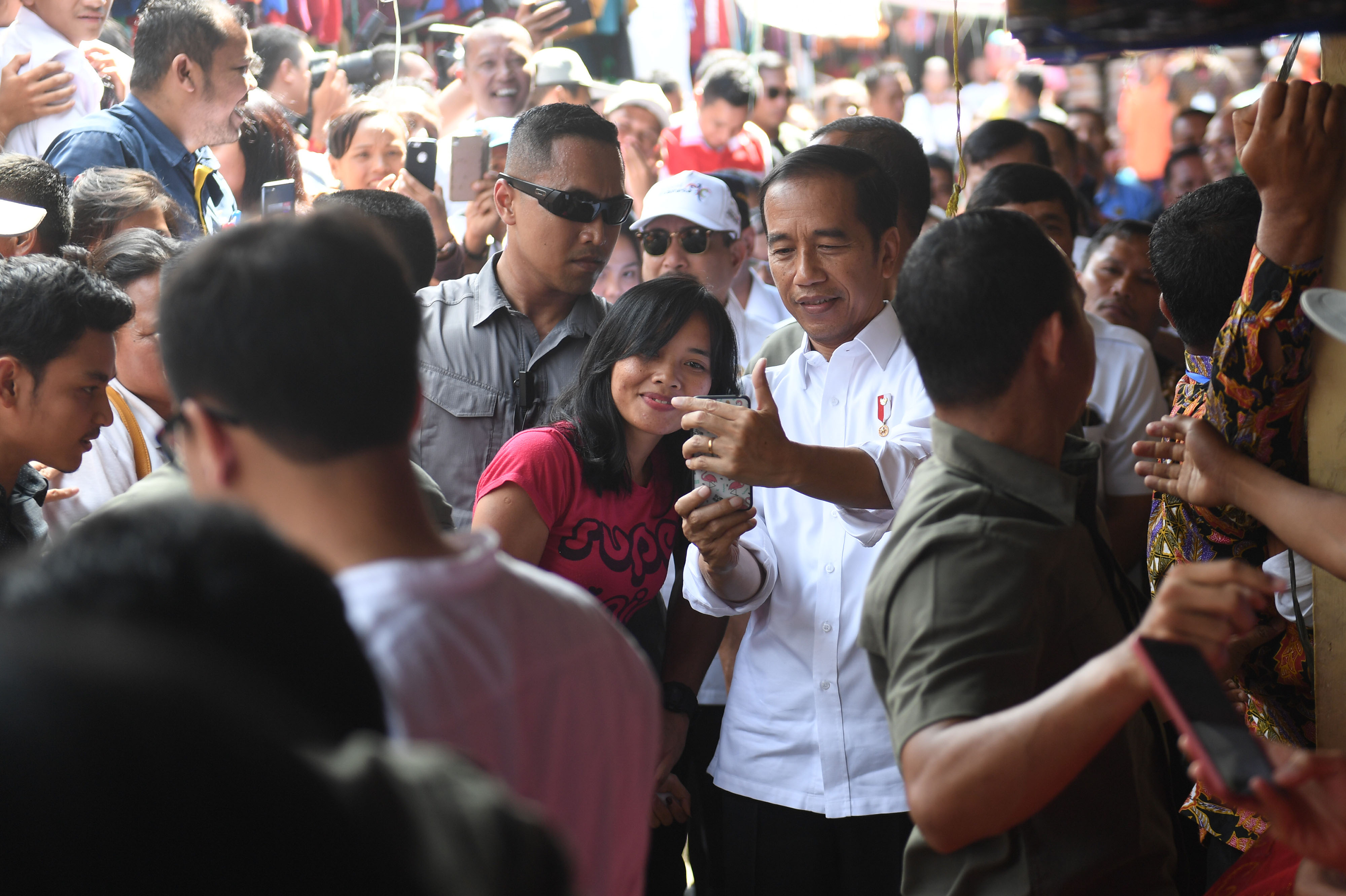 Presiden Joko Widodo melayani ajakan swafoto warga saat meninjau Pasar Onan Baru di Samosir, Sumut, Rabu (31/7)