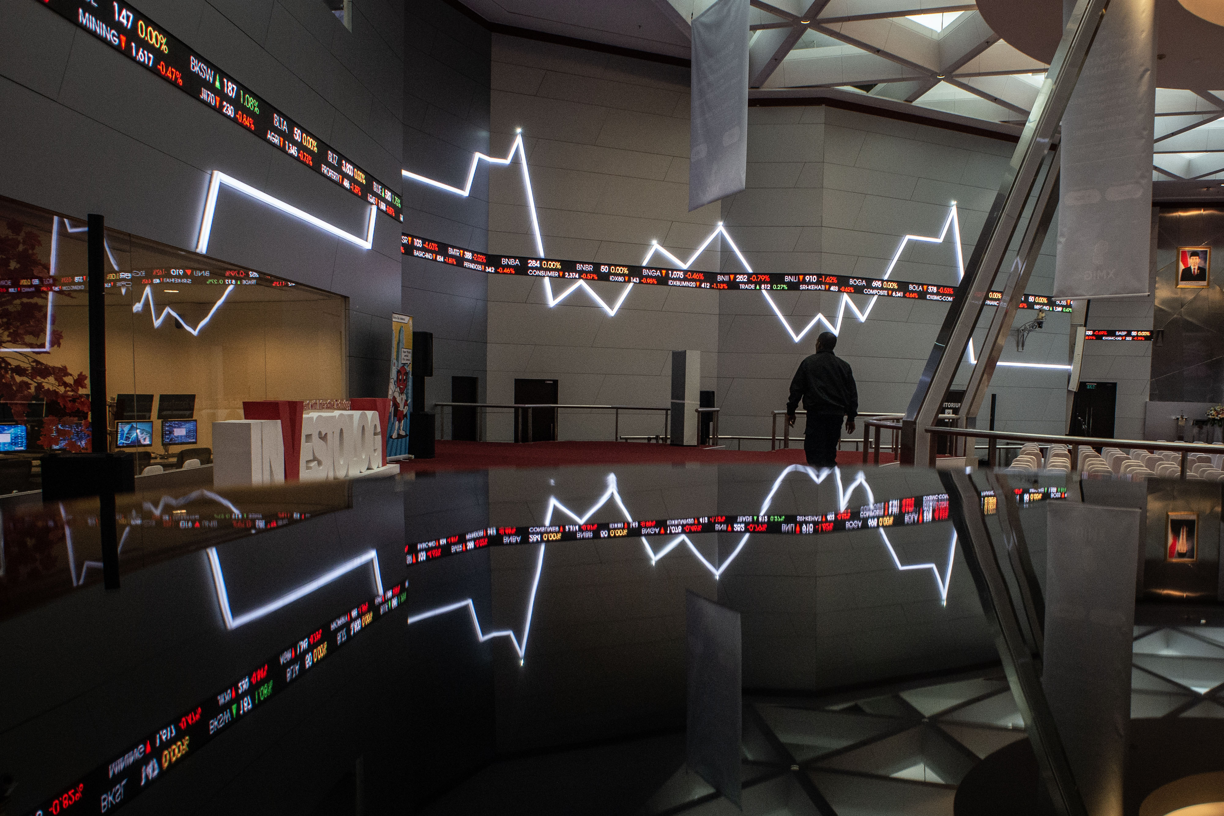  Karyawan beraktivitas di dekat grafik pergerakan saham di gedung Bursa Efek Indonesia, Jakarta.