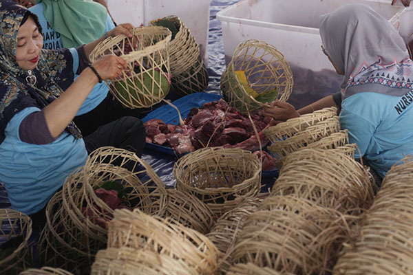 Panitia Qurban sedang memasukan daging qurban dengan kemasan ramah lingkungan