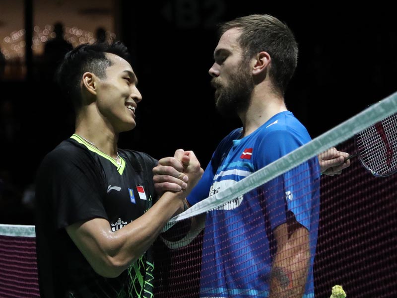 Jonatan Christie (kiri) menjabat tangan lawannya Jan O Jorgensen seusai laga 16 besar di Kejuaraan Dunia Bulu Tangkis