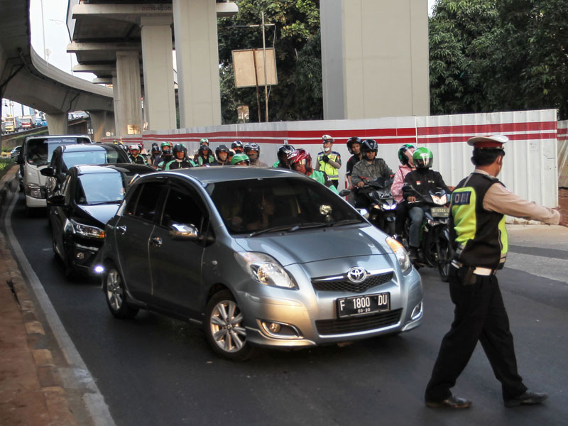 Petugas Kepolisian melakukan penindakan terhadap kendaraan roda empat yang melanggar aturan ganjil-genap di Jalan MT. Haryono, Jakarta.