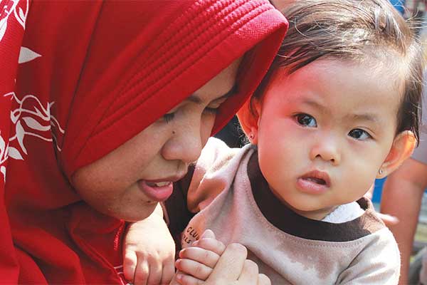 Warga menggendong Aisyah yang selamat dalam sebuah kecelakaan truk pengangkut tanah menimpa minibus.