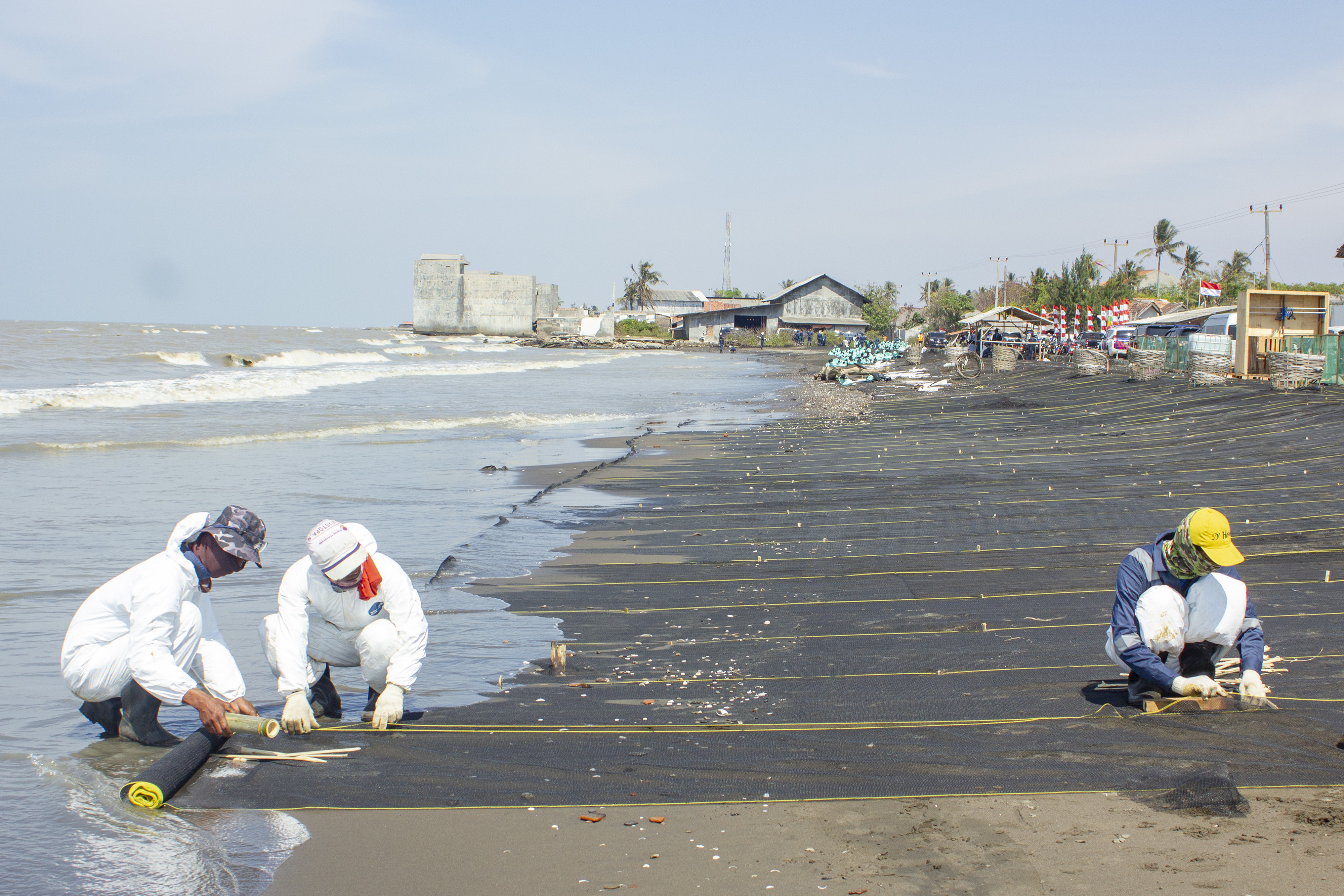 Petugas menyelesaikan pemasangan kain waring atau jaring di pesisir Pantai Cemarajaya, Cibuaya, Karawang