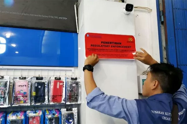 Petugas Bank Indonesia saat menempelkan stiker penertiban penjualan valuta asing di Kabupaten Belu yang berbatasan dengan Timor Leste.  