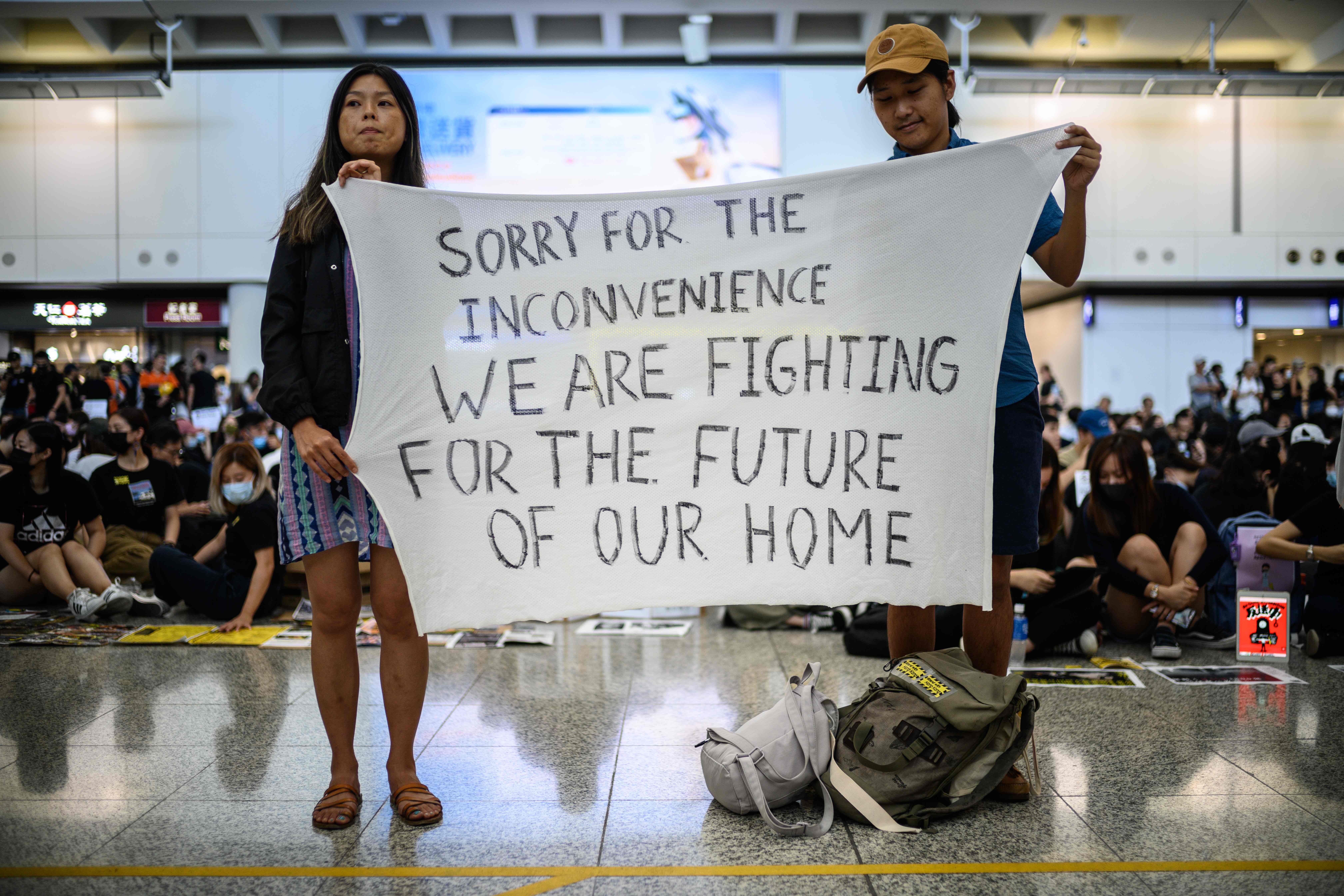  Demonstran membentangkan spanduk di Bandara Hong Kong, Jumat (9/8). Mereka menentang RUU ekstradisi. 