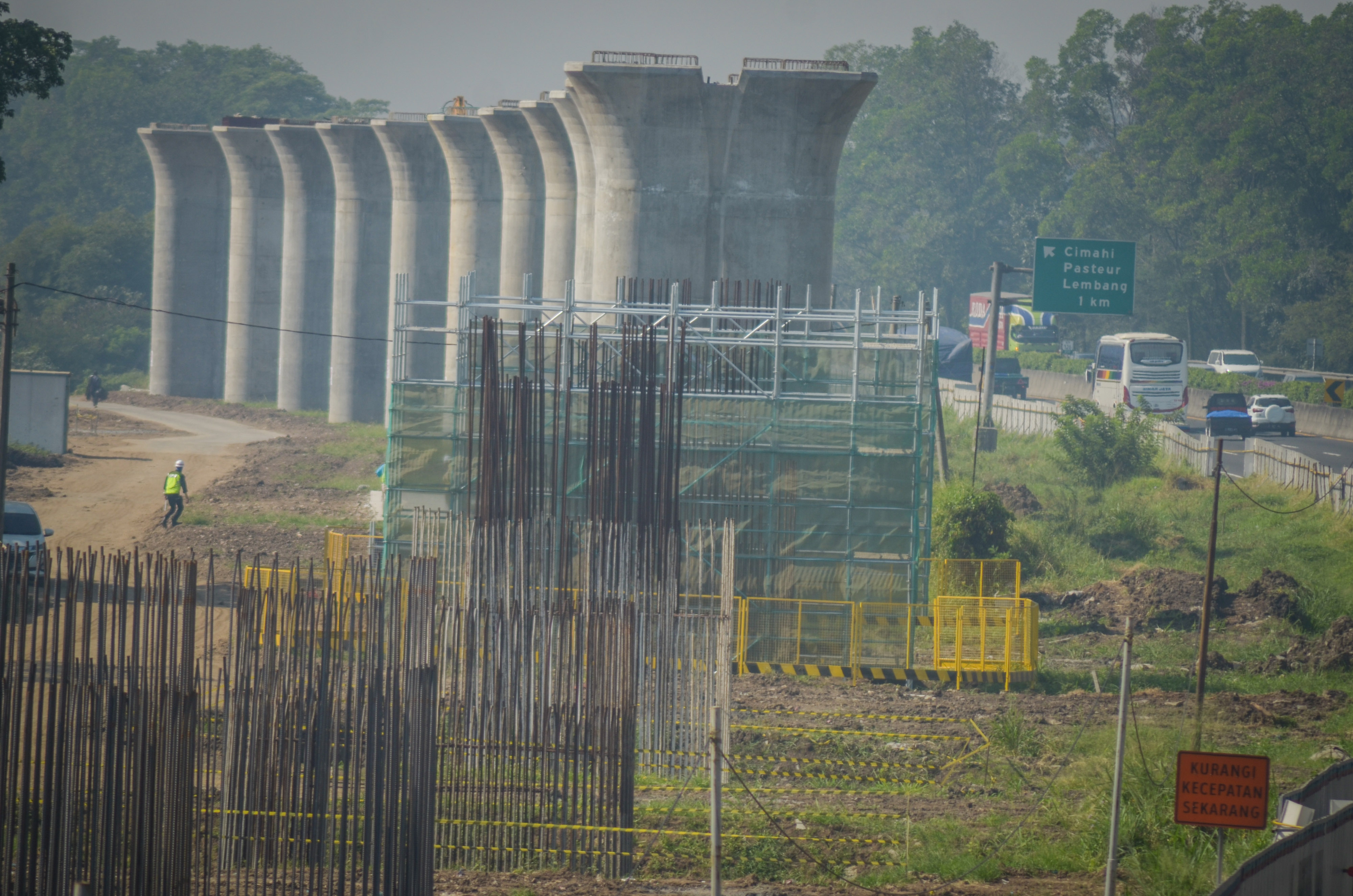  Pekerja melintas di antara proyek pembangunan lintasan kereta cepat Jakarta-Bandung di Cibeber, Cimahi, Jawa Barat.