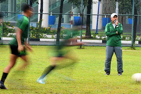 Pelatih Timnas U-18 Indonesia Fakhri Husaini (kanan) memperhatikan para pemain saat latihan.