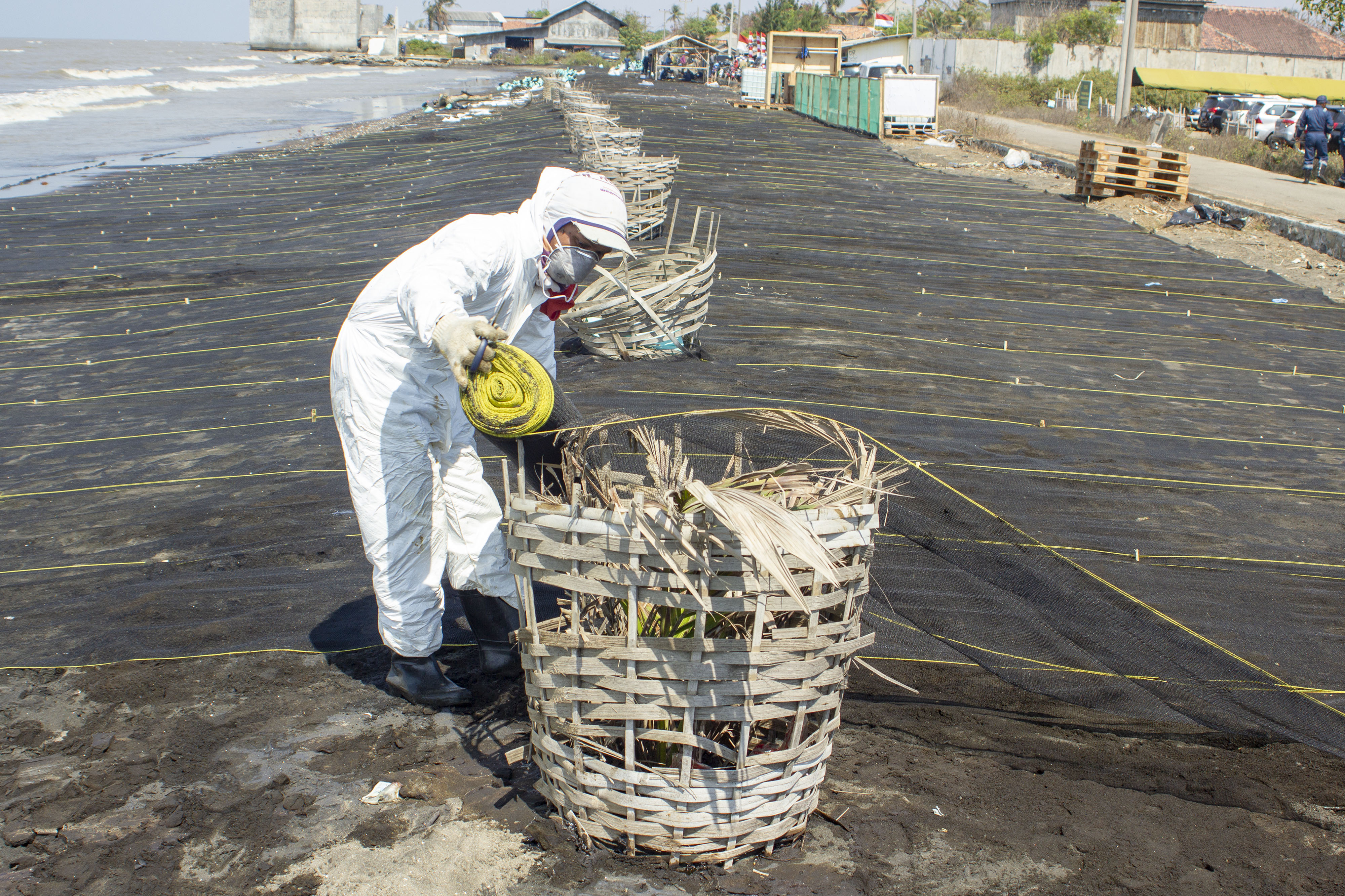 Petugas menyelesaikan pemasangan kain waring atau jaring di pesisir Pantai Cemarajaya, Cibuaya, Karawang, Jawa Barat, Rabu (7/8/2019). 