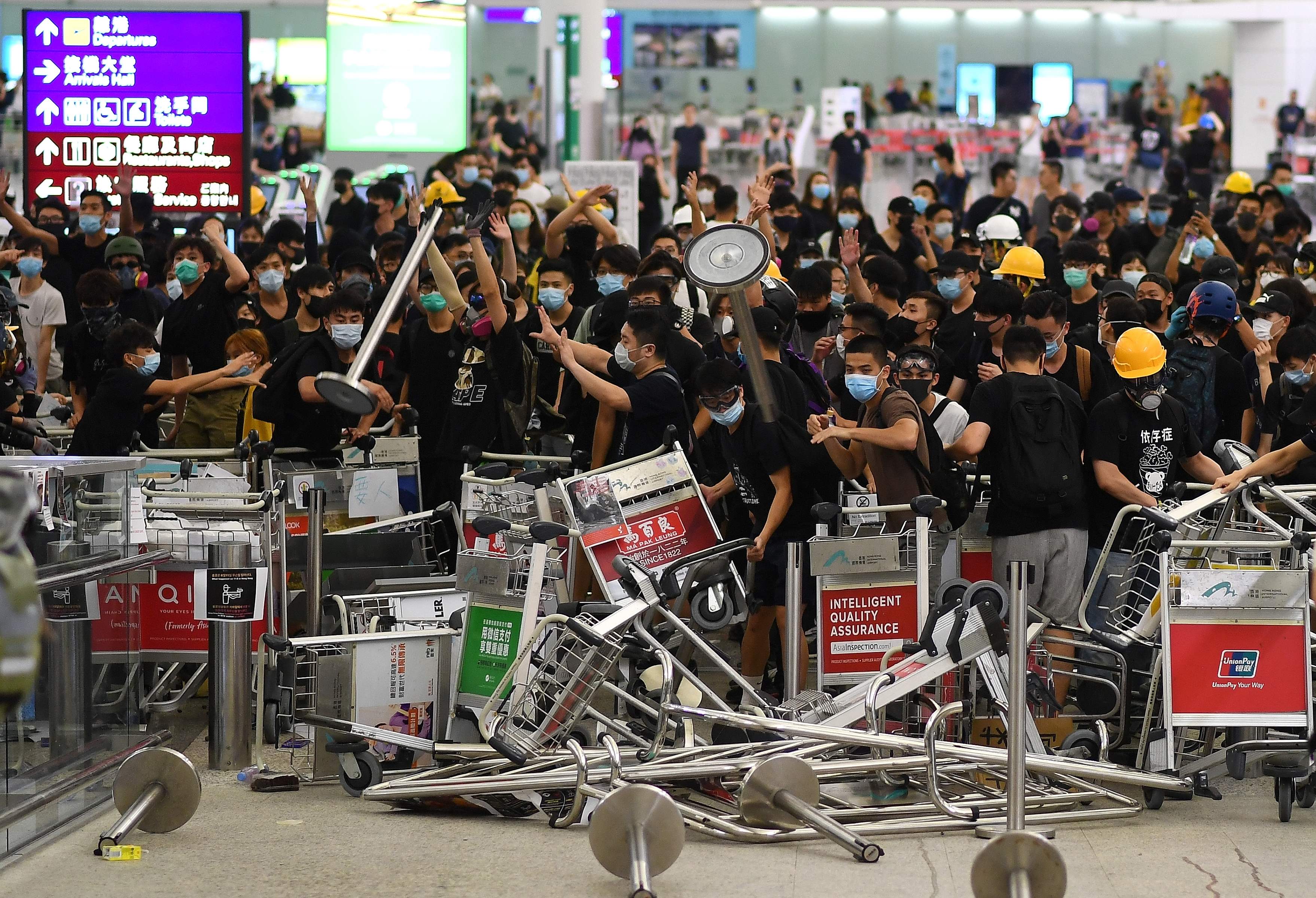 Demonstran membuat blokade pintu masuk bandara Hong Kong setelah terlibat bentrok dengan polisi.