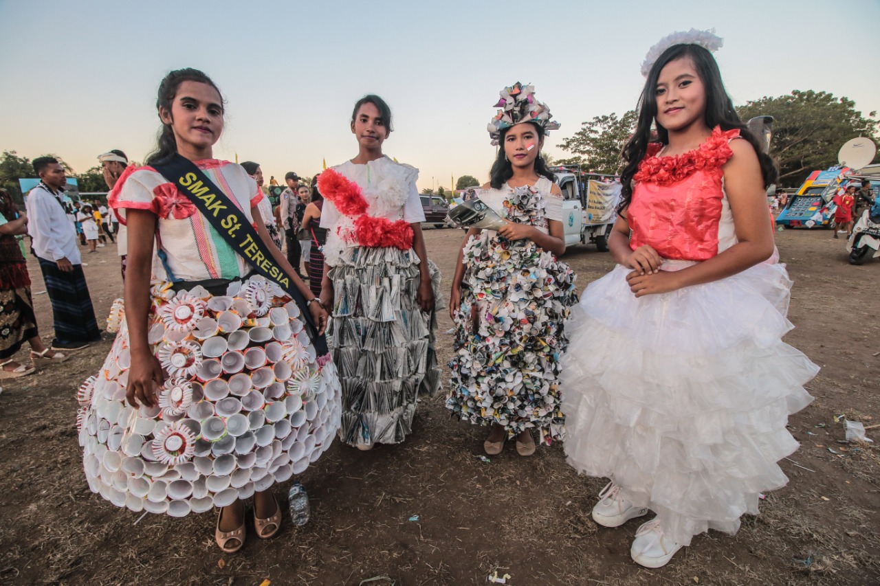 Empat siswi mengenakan pakaian dari sampah plastik serta koran bekas.