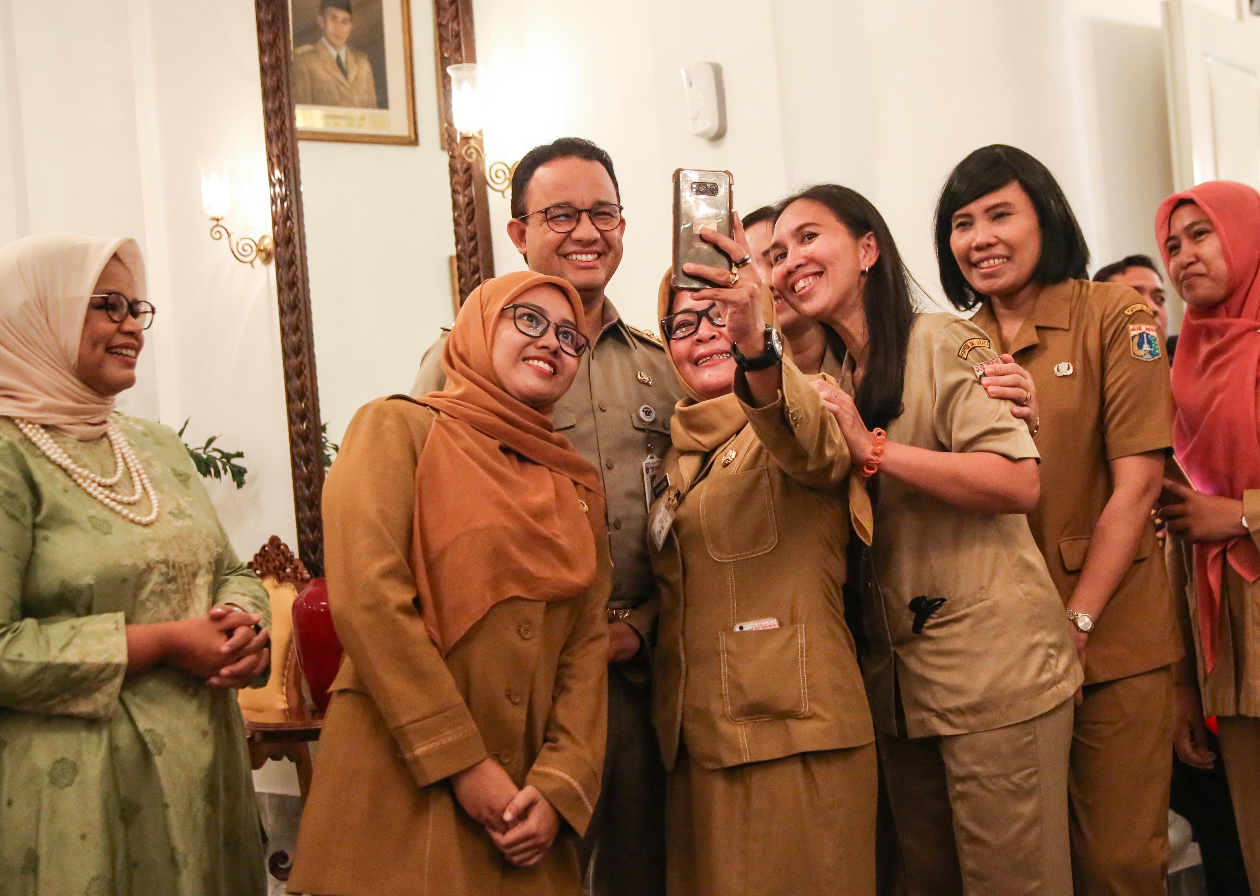 Gubernur DKI Jakarta Anies Baswedan (tengah) disaksikan Istri Ferry Farhati (kiri) melayani foto bersama Aparatur Sipil Negara 