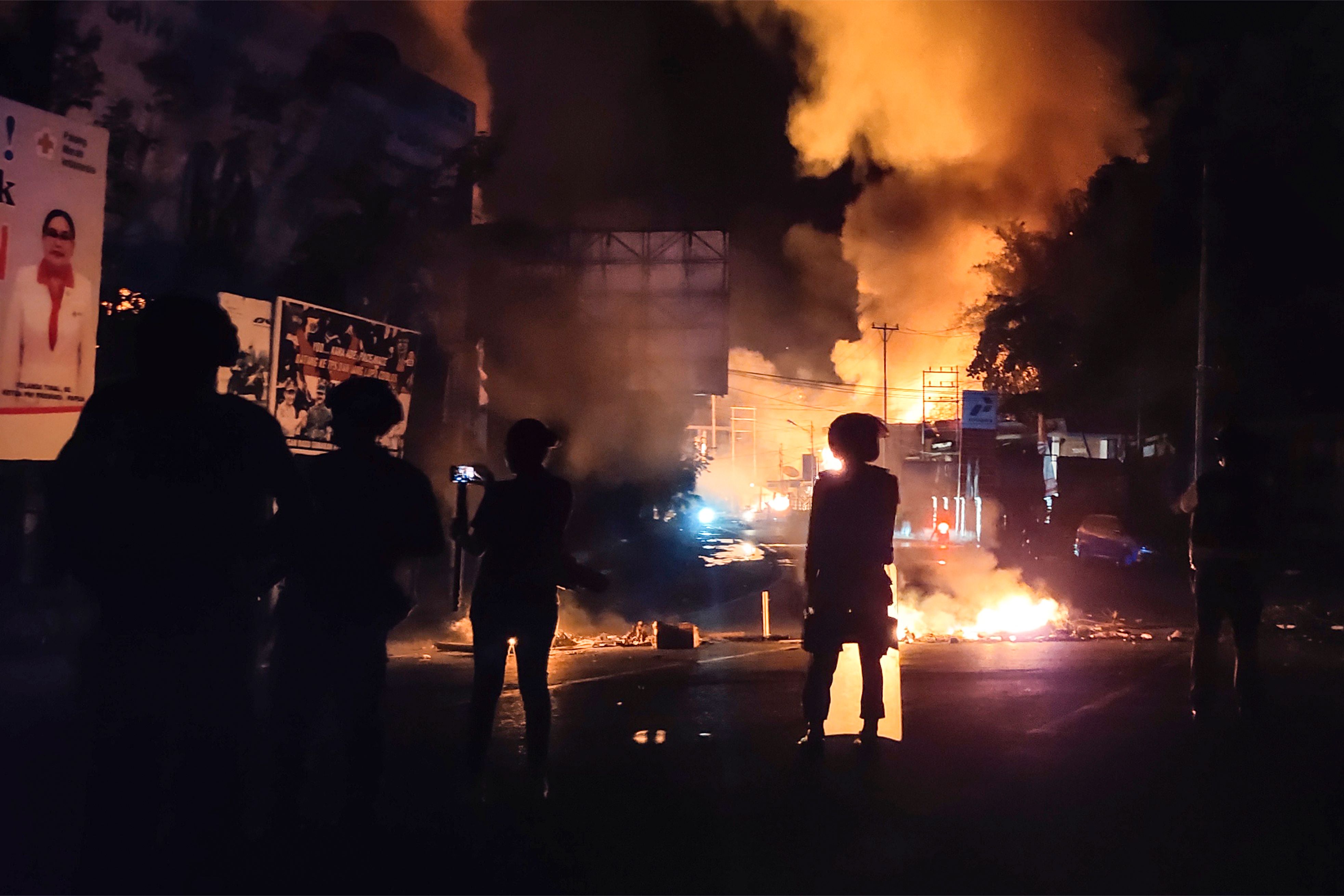 Personel polisi berjaga-jaga di depan bangunan yang terbakar di Jayapura selepas aksi unjuk rasa pada Kamis (29/8).